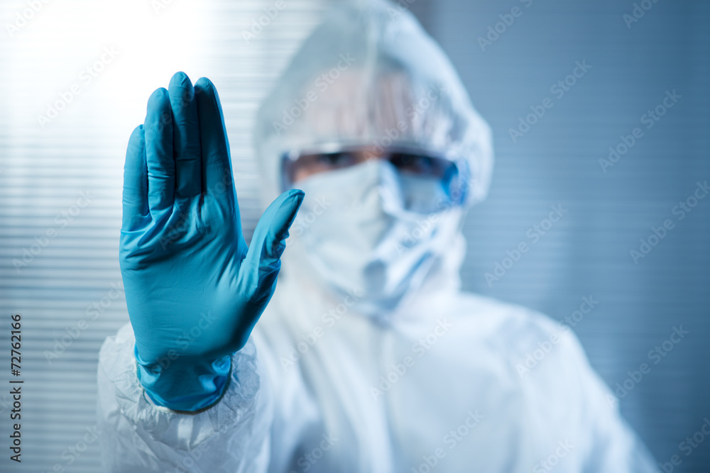Female scientist in protective hazmat suit with hand raised Female scientist in protective hazmat suit with hand raised
