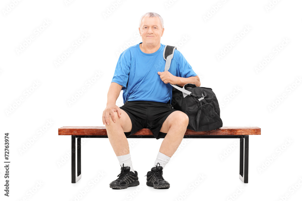 Active senior carrying a sports bag seated on bench Active senior carrying a sports bag seated on bench