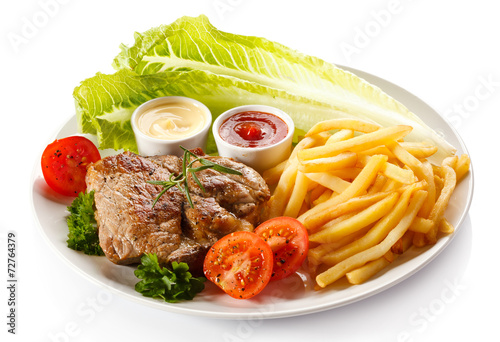 Barbecued steak, French fries and vegetables
