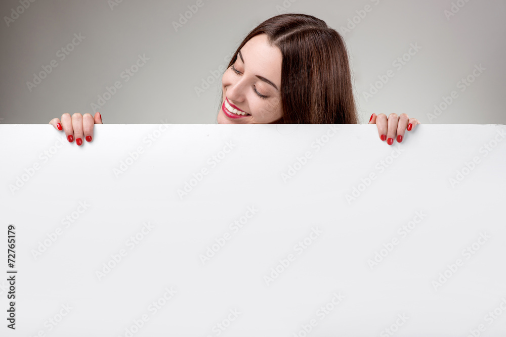 Woman showing white billboard over grey background in studio Woman showing white billboard over grey background in studio