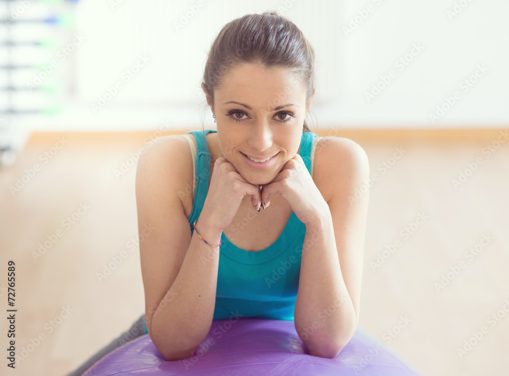 Smiling woman exercising at gym with fitness ball