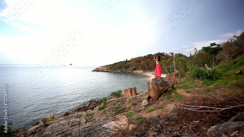 Young woman standing on a rockis taking photo. Koh Samui. photo