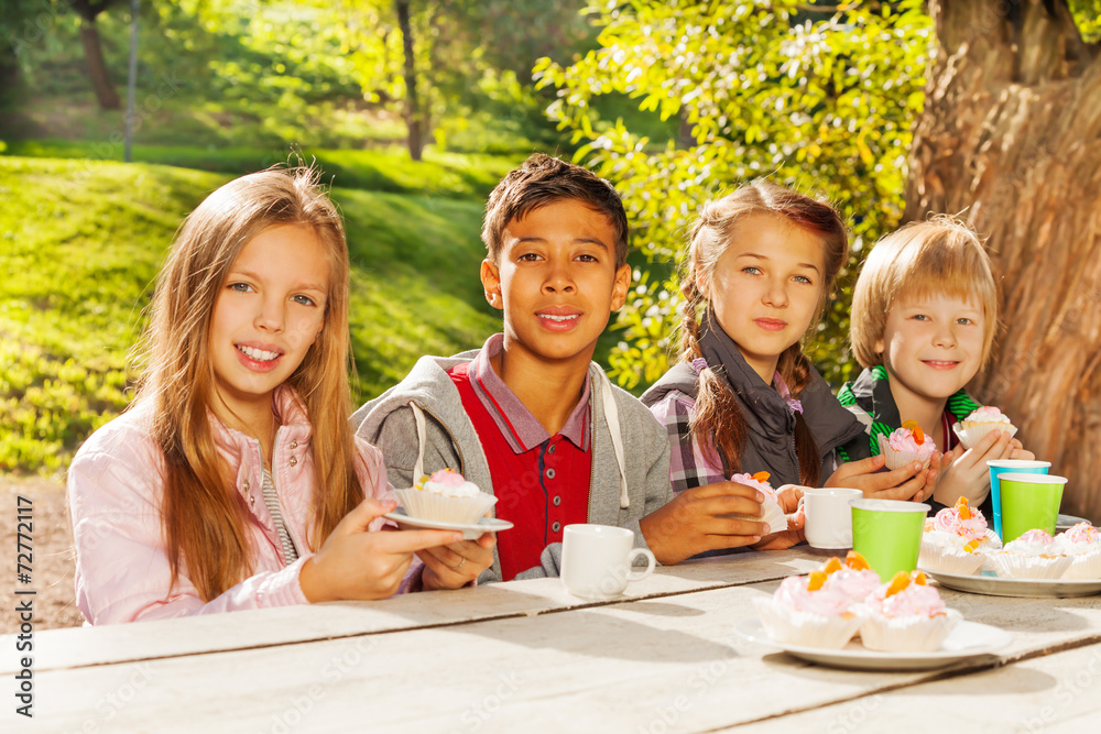 Happy children drinking tea with cupcakes Happy children drinking tea with cupcakes