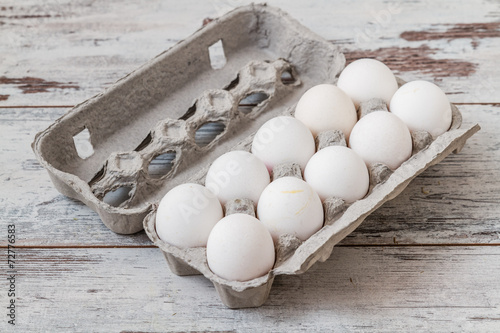 White Eggs in Modern Cardboard Packing on White Wooden Background
