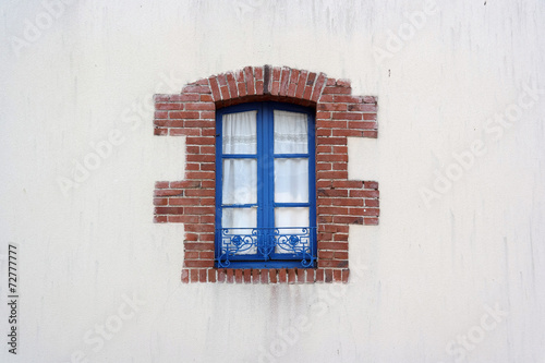 Blue Window frame edged with bricks in Brittany
