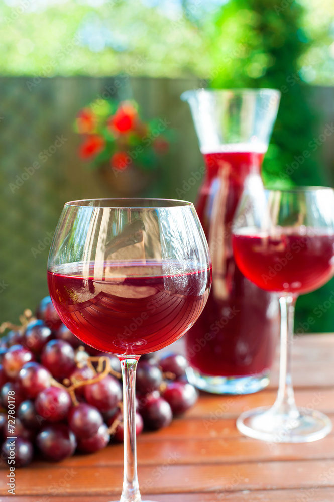 Two glasses of delicious homemade red wine with grape.