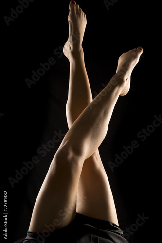 woman legs up on black back lit crossed at knees