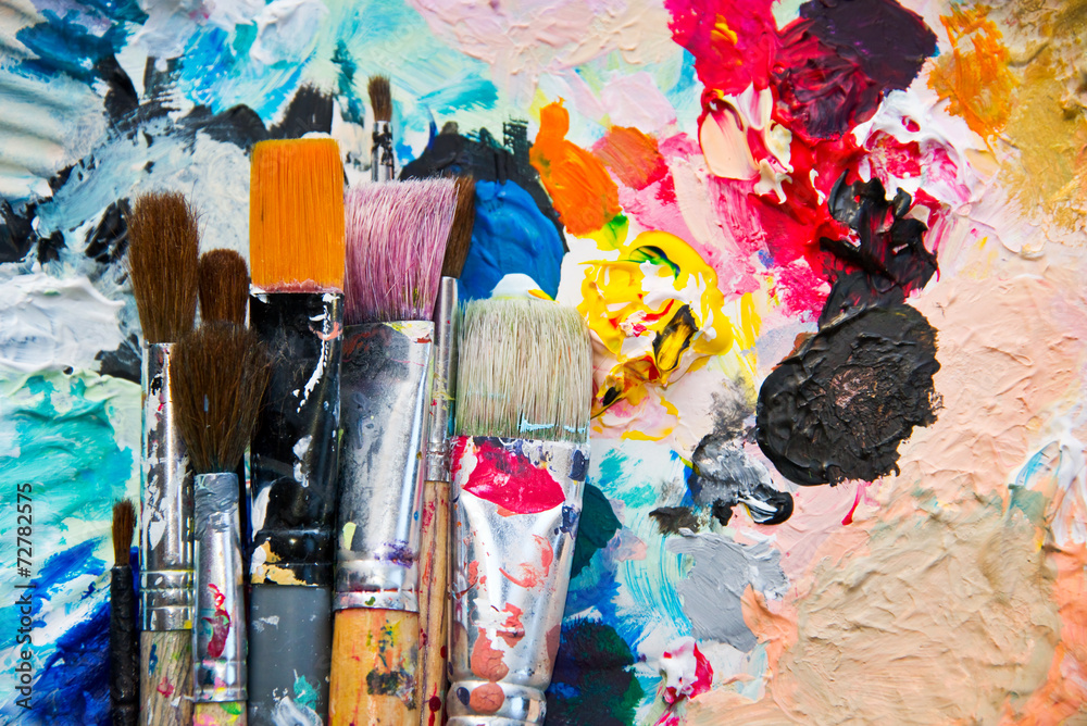 Fototapeta premium Used paint brushes on a colorful painter palette