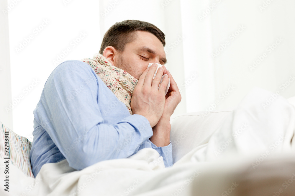 ill man in scarf blowing nose at home ill man in scarf blowing nose at home