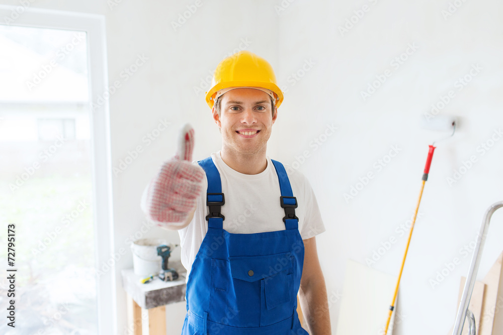 smiling young builder in hardhat showing thumbs up smiling young builder in hardhat showing thumbs up