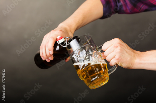 young man pouring beer from bottle into mug
