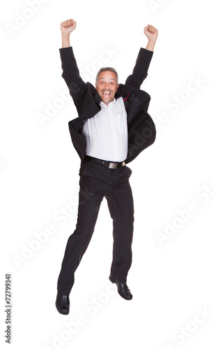 Successful Businessman Jumping With Hands Raised