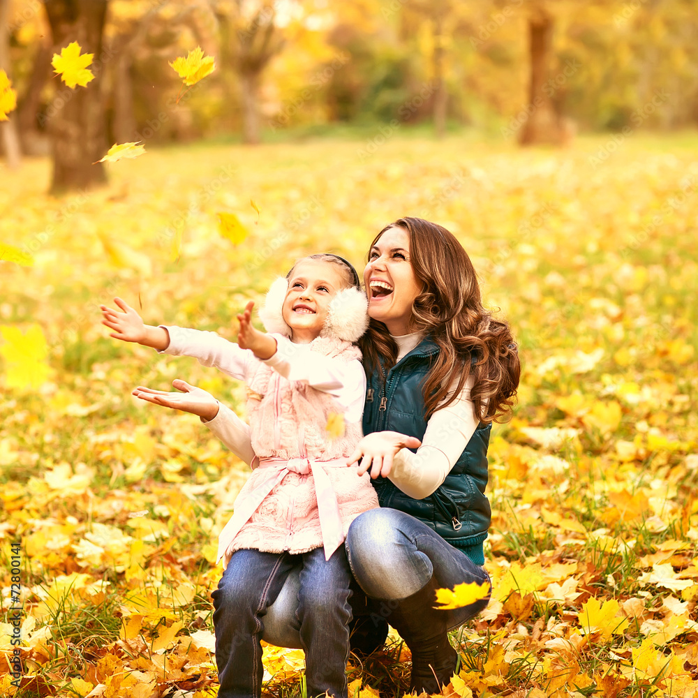 Mother and daughter having fun in the autumn park among the fall Mother and daughter having fun in the autumn park among the fall