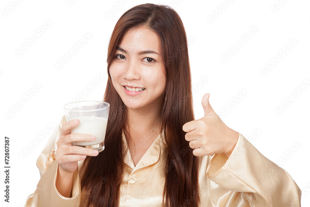 Happy Asian woman in pajamas drink milk show thumbs up Happy Asian woman in pajamas drink milk show thumbs up