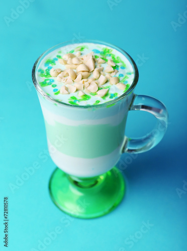 Mint milk dessert with nuts in glass on color background