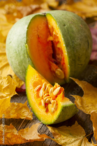 green pumpkin and pumpkin slice on wooden background strewn wit