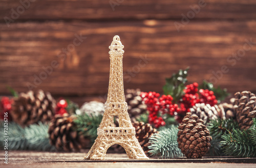 Photography Eiffel tower toy with pine branches on a table.