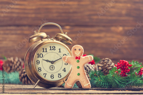Alarm clock near Pine branches and gingerbread on wooden table.