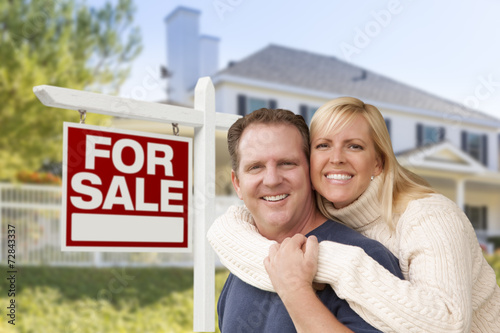 Couple in Front of New House and Real Estate Sign