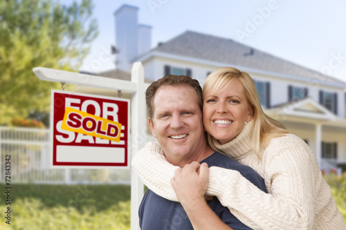 Couple in Front of New House and Sold Sign