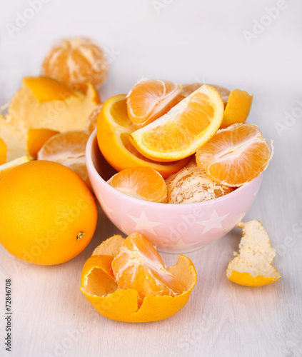 Sweet tangerines and oranges on table in bowl in room