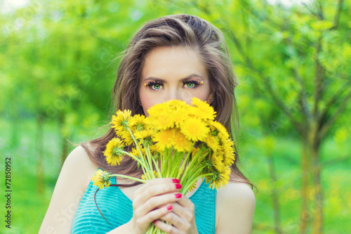beautiful girl keeps yellow dandelions in the hands