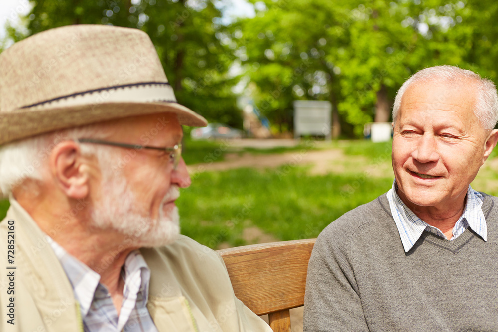 Zwei Senioren reden auf Bank im Pflegeheim miteinander StockFoto
