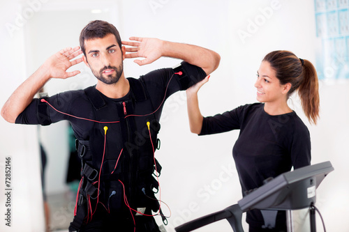  Female coach giving man ems electro muscular stimulation exerci photo