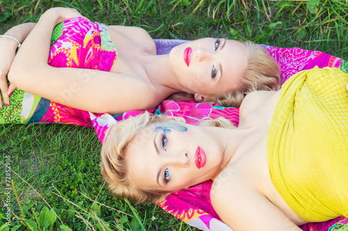 girls sisters with makeup lie on a bright blanket in a Park