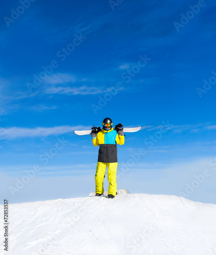Snowboarder hold snowboard on top of hill