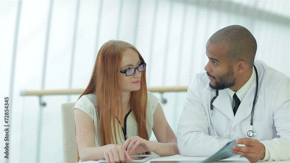 Doctor talking to patient while sitting at a table Doctor talking to patient while sitting at a table