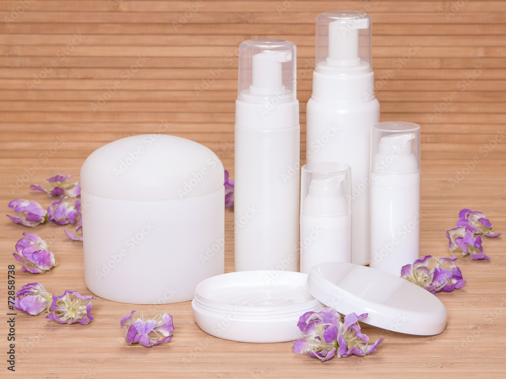 Open jar of cream and other body care cosmetics with flowers