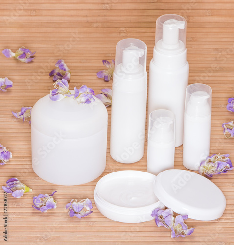 Open jar of cream and other body care cosmetics with flowers