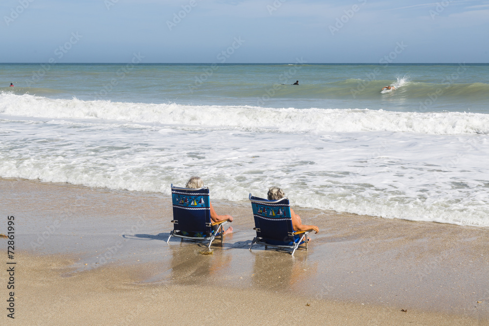Tourists on the beach looks out to sea and waves Tourists on the beach looks out to sea and waves