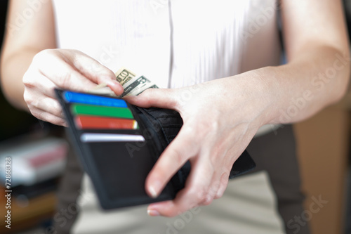 Black purse with money in woman`s hand