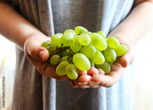 sprigs of green grapes in hands