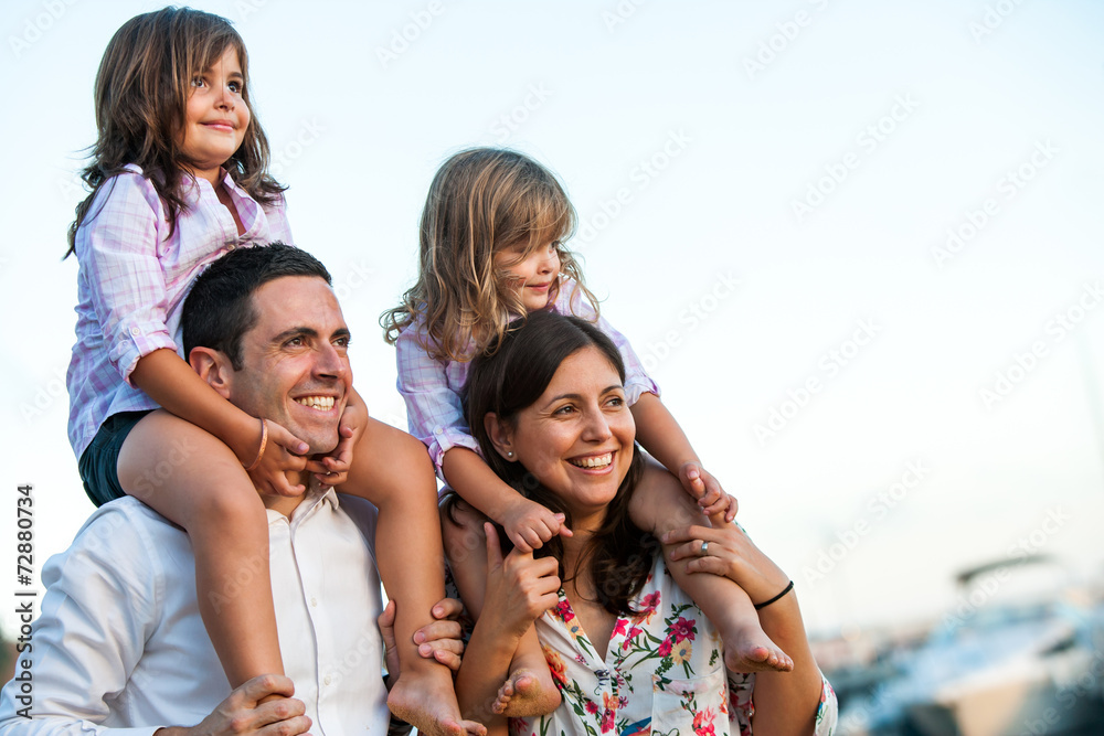 Young couple with kids on shoulders outdoors. Young couple with kids on shoulders outdoors.