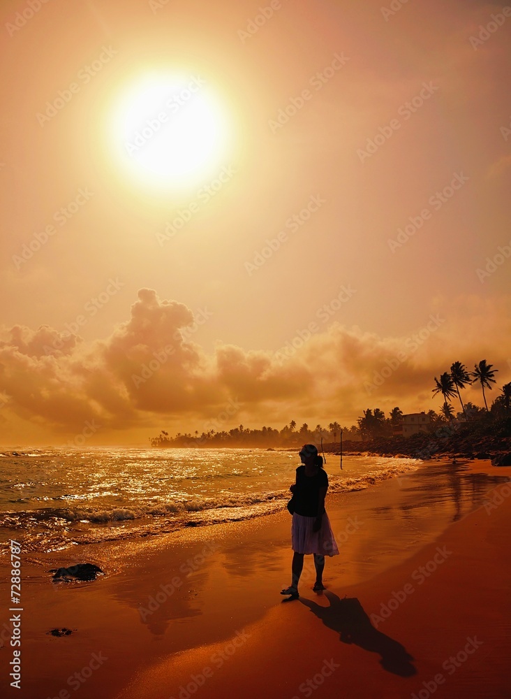 Fototapeta premium Woman on beach at sunset.