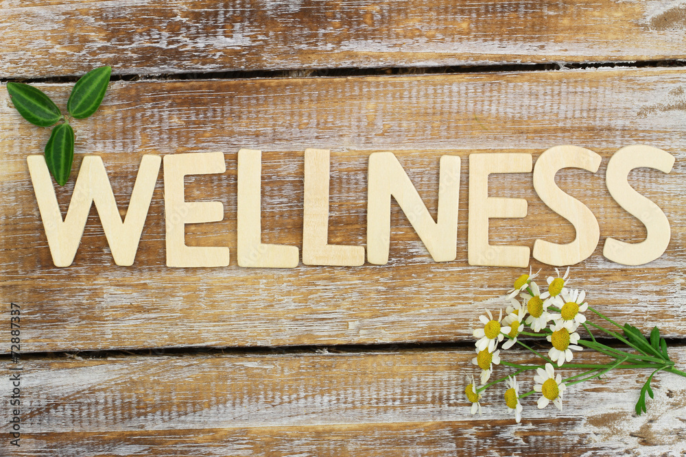 Wellness written with wooden letters, chamomile flowers on wood - obrazy, fototapety, plakaty 