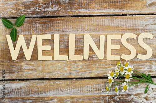Wellness written with wooden letters, chamomile flowers on wood