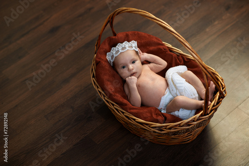 newborn with a crown in  basket on  floor