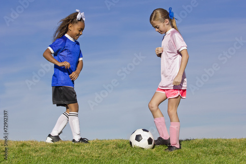 Two young girls playing soccer (simple background)