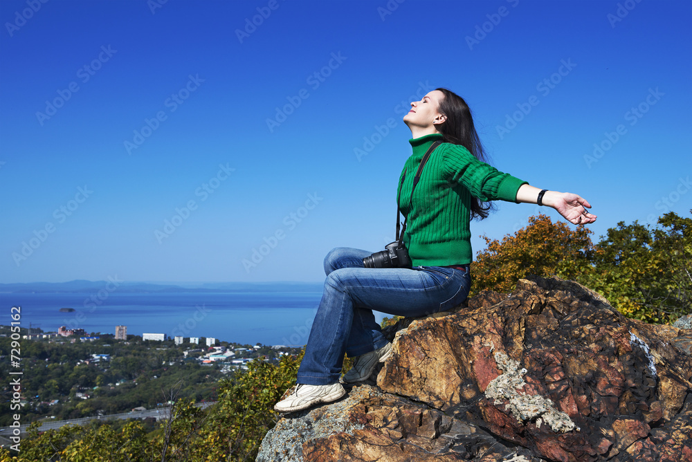 Young woman sitting on the rock with camera