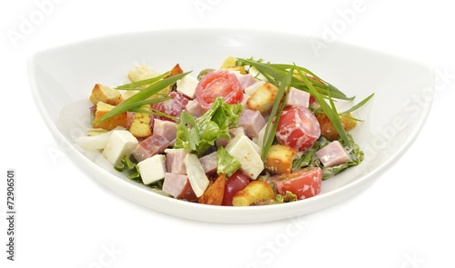 Salad with gammon, cheese and vegetables on white plate