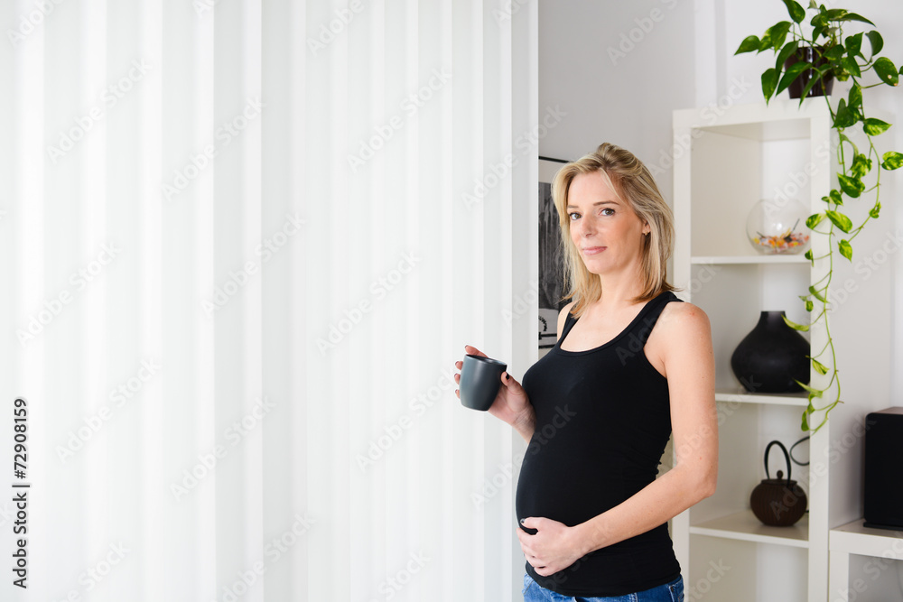 cheerful mature pregnant woman at home drinking a cup of tea