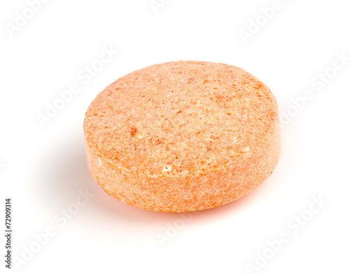 Macro closeup of orange vitamin c chewable tablet isolated on wh