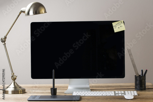 Image of a big computer screen with a lamp and stationary items