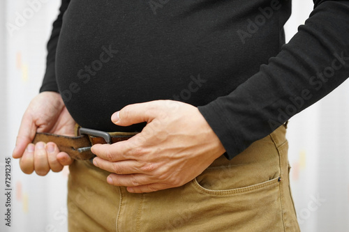 men can not fasten his belt on  pants due to big stomach photo