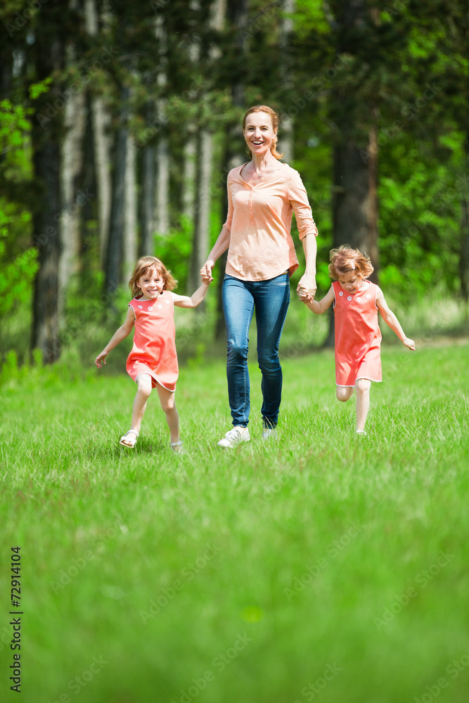Mutter mit Zwillingsmädchen macht Spaziergang Mutter mit Zwillingsmädchen macht Spaziergang