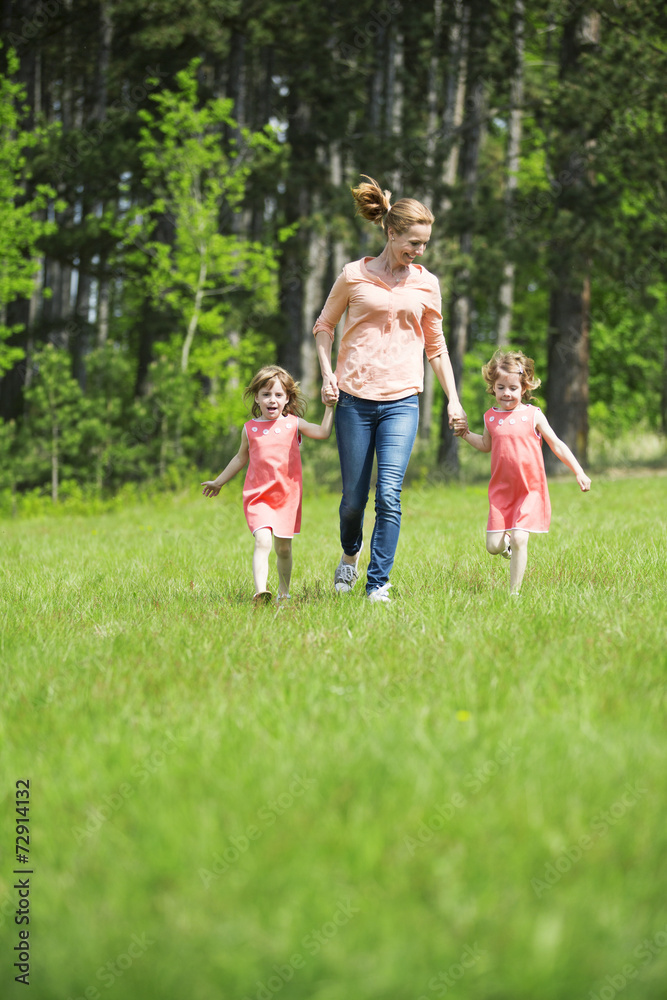 Mutter mit Zwillingsmädchen macht Spaziergang Mutter mit Zwillingsmädchen macht Spaziergang